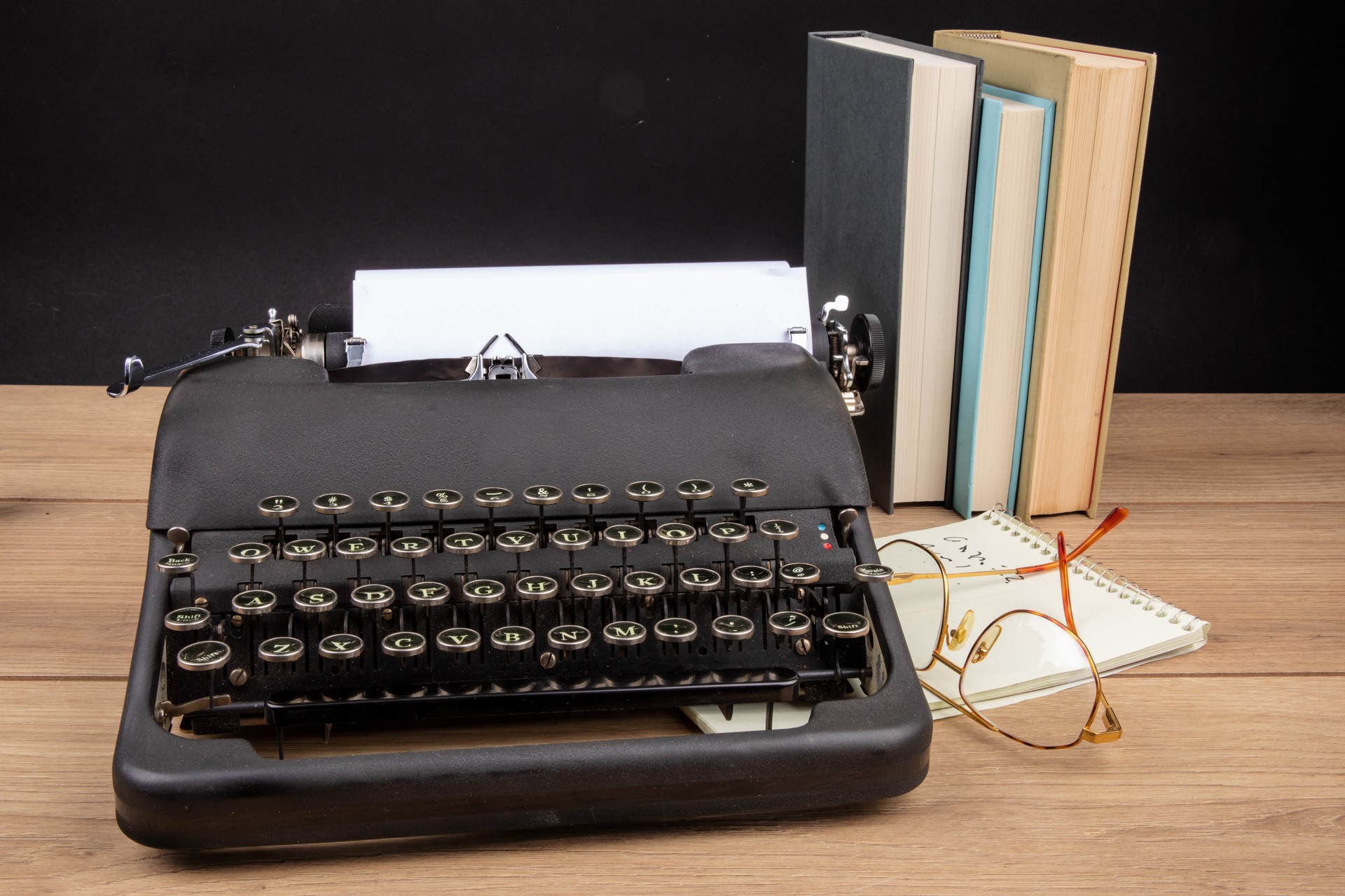 an old black portable typewriter with a steno pad and eye glasses and text books as at a secretary's desk